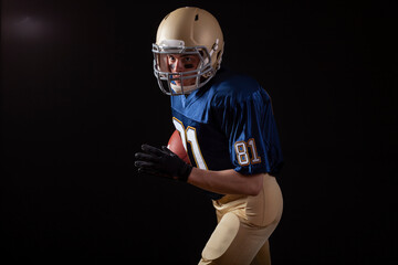 Young football player in running action on a dark background