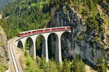 Fotobehang Landwasserviaduct Landwasserviaduct in de bergen van Davos bij Filisur. Mooie oude stenen brug met een rijdende trein. lentetijd