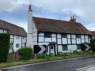Fototapeta na wymiar Sonning, UK. English countryside in Berkshire. Medieval village street view. Old tudor timber framed cottages with chimney along the road with bush and front garden. 