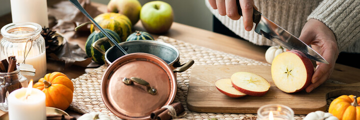 Young woman preparing hot autumn drink: mulled wine with spices, fruits. Natural ingreduents: cinnamon, anise, cardamon, clove, apple, orange. Cozy home atmosphere banner