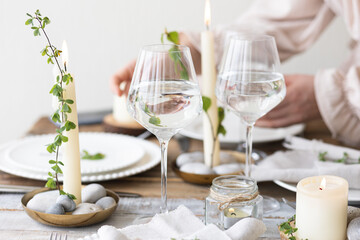 Rustic zero waste wedding decor with natural elements. Wooden table, candles, linen napkins, branches with green leaves. Eco-friendly decoration for the special dinner. Romantic and cozy place