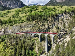 Photo sur Plexiglas Viaduc de Landwasser Viaduc de Landwasser dans les montagnes de Davos près de Filisur. Beau vieux pont de pierre avec un train en mouvement. Temps de printemps
