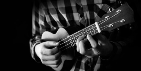 A young man playing ukulele in close up view