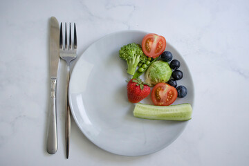 Vegetables and fruits on a plate on a light background