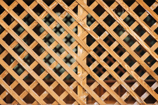 Wooden fence, lattice in rhombuses, squares close-up. Photography, background.
