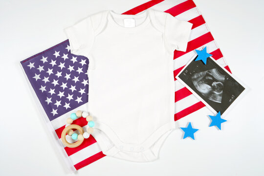 Baby Romper Onesie Bodysuit Jumpsuit Ultrasound Mockup. Patriotic Fourth of July, Independence Day theme craft product mockup styled with USA Stars and Stripes flag against a white background.