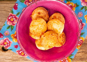 Minas Gerais cheese bread, hot, on a pink bowl, on a flowered picnic tablecloth, top view