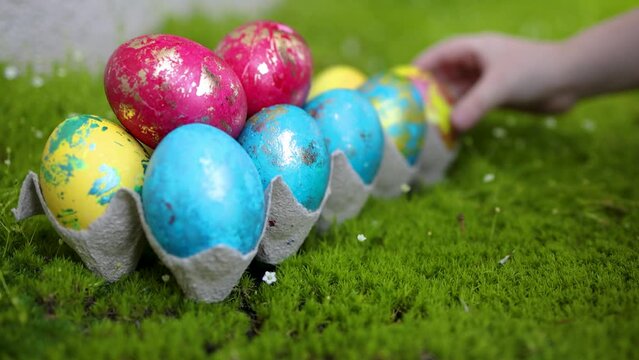 spring egg hunt. little hands grabbing the colorful easter eggs on the fresh grass