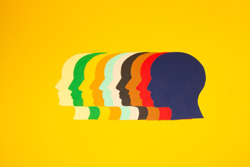 colorful paper heads looking at one point on a yellow background, all the power of the mind focused on solving problems