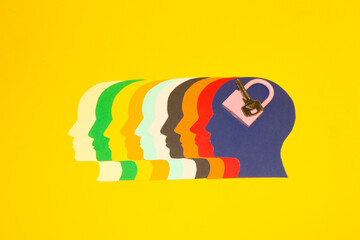 colorful paper heads facing left and the last blue head with key and padlock, security creative thinking about safe solutions, yellow background
