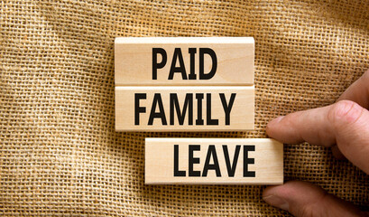 Paid family leave symbol. Concept words Paid family leave on wooden blocks. Doctor hand. Beautiful canvas table canvas background. Business medical and paid family leave concept. Copy space.