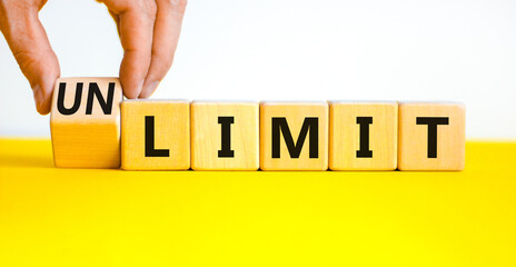 Limit or unlimit symbol. Businessman turns wooden cubes and changes the concept word Limit to Unlimit. Beautiful yellow table white background. Business limit or unlimit concept. Copy space.