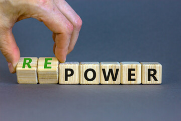 Power or repower symbol. Businessman turns wooden cubes and changes concept words Power to Repower. Beautiful grey table grey background. Business ecological power or repower concept. Copy space.