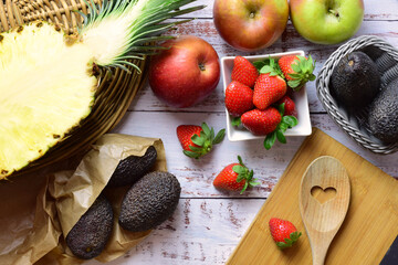 Varied and also tropical fruit, pineapple, avocado, on rustic white wood, zenith view. Healthy food.