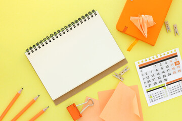 notepad with orange pen and orange notepad on yellow background. The concept of beautiful high quality and resolution photos