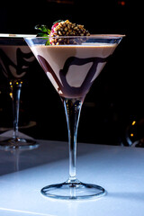 Chocolate drink with whipped cream, strawberry and pieces of black chocolate on a dark background.