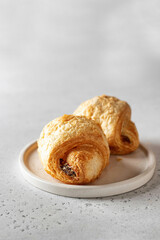 Fresh croissants on a white plate on a light background