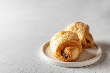 Fresh croissants on a white plate on a light background