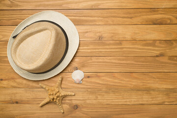 Wicker hat and seashells on wooden background, top view