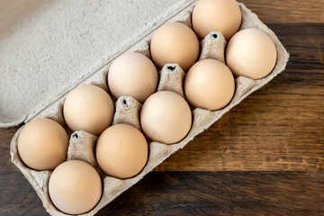 Top view, ten chicken eggs in a cardboard tray on the table.