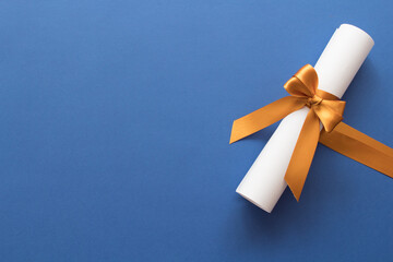 Diploma de graduado con cinta dorada en fondo azul