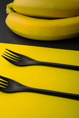 Forks on the table. Black forks on a yellow background and a banana on a black one. Black and yellow. Concept. Beautiful background