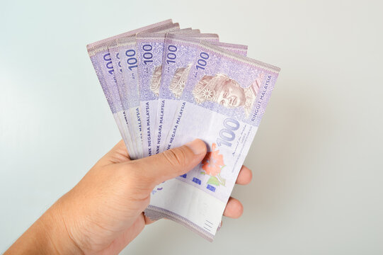 Hand holding stack of ringgit Malaysia money banknotes