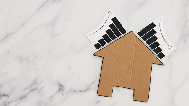 mortgages rentals and property prices increasing and decreasing, house icon made of cardboard with graph showing stats going up and down