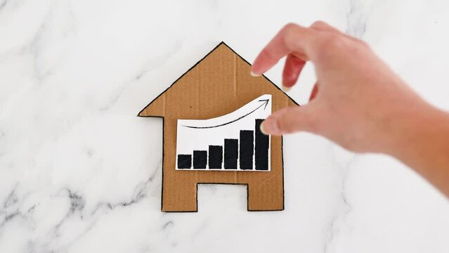mortgages rentals and property prices increasing, house icon made of cardboard with graph showing stats going up