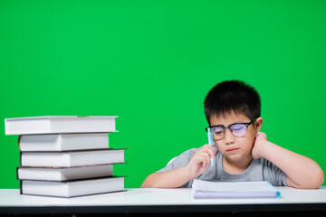 boy doing homework on green screen, child writing paper, education concept, back to school
