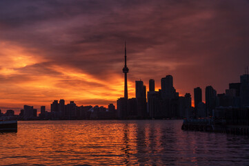 Fototapeta premium Summer sunset view from Toronto Islands across the Inner Harbour of the Lake Ontario on Downtown Toronto skyline with skyscrapers under a magnificent sky