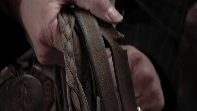 Hands of a Gaucho holding Horse Leather Bridles inside a Stable in Argentina. Close Up.