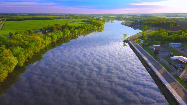 Amazing sky with rippled clouds, mirrored in tranquil river at daybreak, moving aerial view.
