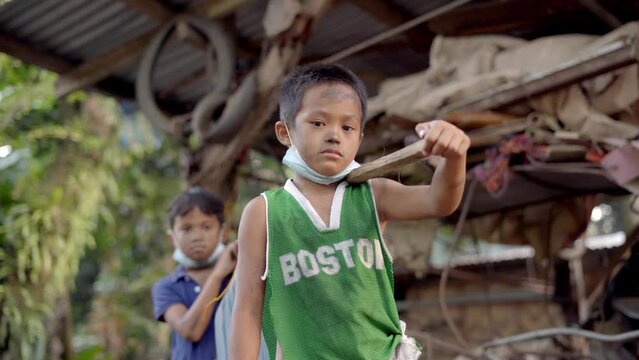 Sad Portrait Of Two Poor Kids With A Wooden Pole Carrying Together Heavy Gallons Of Water. Traditional Way Of Fetching Water In Philippines. - Low-Angle Shot