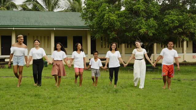 A Diverse Group Of People Walking Together In Barefoot Holding Each Other Hands Outside The School Building In The Philippines. - Handheld Backwards