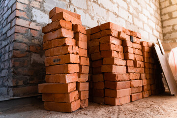 Stacked red bricks construction site against the background of a wall of white gas block