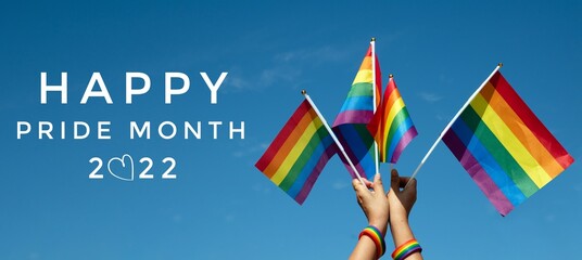 'HAPPY PRiDE MONTH 2022' on bluesky and rainbow flags background, concept for lgbtq+ celebrations in pride month, june, 2022. - obrazy, fototapety, plakaty
