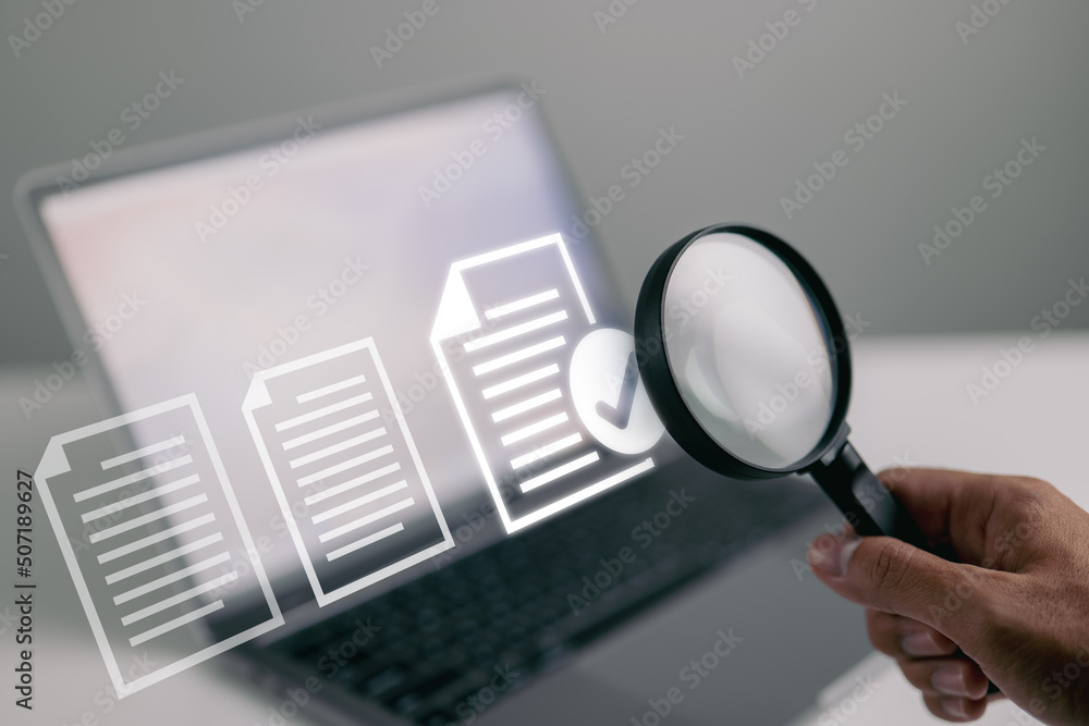 Poster documents and magnifying glass. confirmed or approved document on laptop computer.