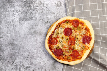 Homemade pizza with pepperoni and olives on a dark grey background. Top view, flat lay