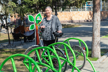 senior woman walking in the park with a bicycle, sunny day looking at camera