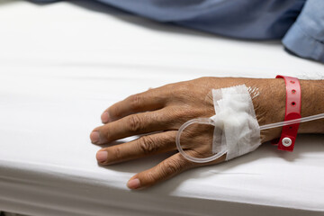Close up the patient's hands and arms are giving the saline solution on bed with copy space.