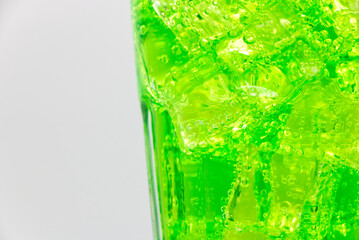 Green sparkling water with Ice in glass over white background.