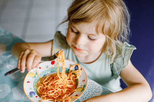 Adorable Toddler Girl Eat Pasta Spaghetti With Tomato Bolognese With Minced Meat. Happy Preschool Child Eating Fresh Cooked Healthy Meal With Noodles And Vegetables At Home, Indoors.