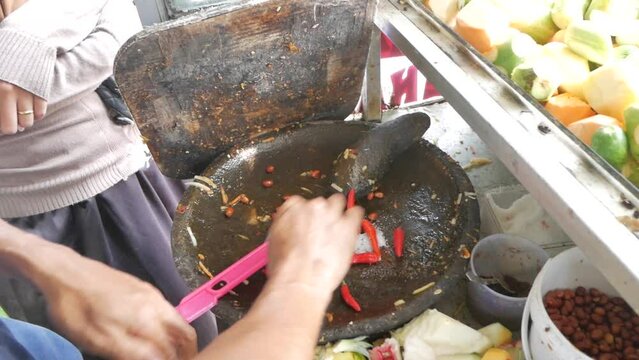 Making sambal with mortal and pestle. Sambal is Sambal is an Indonesian chili sauce or paste typically made from a mixture of a variety of chili peppers with secondary ingredients.