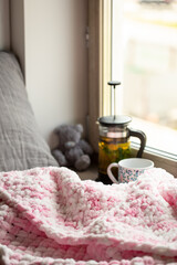 Composition with hand-knitted plaid and tea, the concept of coziness and warmth, a place to relax in the house. Vertical photo.