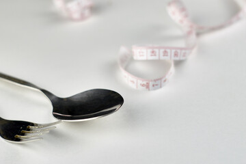 cutlery and a centimeter on a light background with a copy space concept nutrition diet
