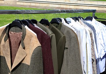 jackets and coats and shirts for sale in the open-air stall of a second-hand clothing market