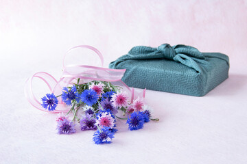 ヤグルマギクの花束と風呂敷包みのデザイン（ペールピンクの背景）	