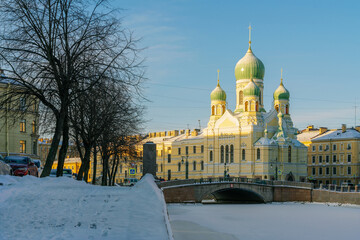 View of Saint Isidore's (Isidorovskaya) Church against the background of the Mogilev Bridge over the Griboyedov Canal on a sunny winter day, St. Petersburg. Russia
