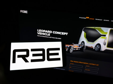 Stuttgart, Germany - 05-20-2022: Person holding smartphone with logo of Israeli company REE Automotive Ltd. on screen in front of website. Focus on phone display.